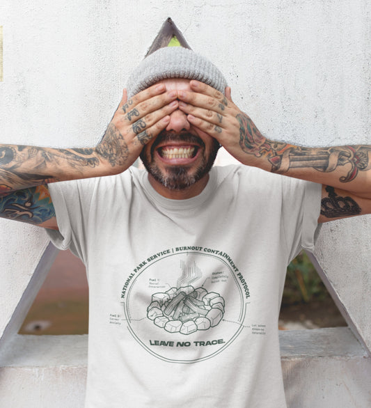 Technisches Diagramm eines Lagerfeuers mit Text Burnout Containment Protocol auf grauem T-Shirt, getragen von einem jungen Mann mit Tattoos. Anti-Gorpcore Streetwear.