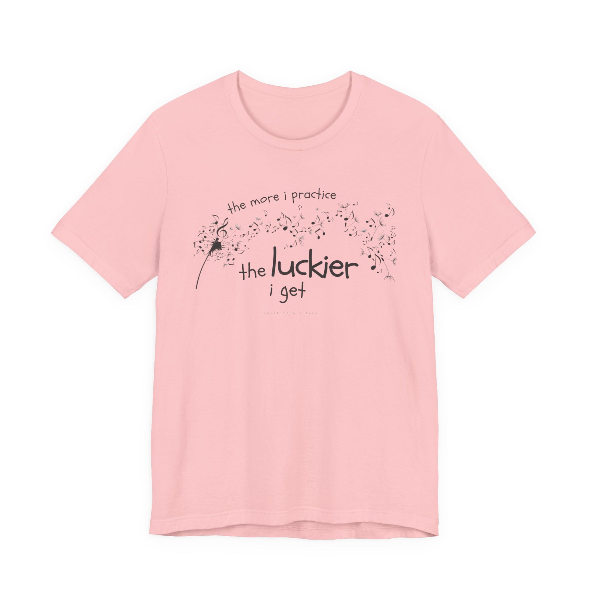 Front view of a pink Bella Canvas t-shirt with a clever music-themed graphic. The design shows a stylized guitar headstock and musical notes above text that reads: ‘The more I practice, the luckier I get.’ Soft 100% cotton shirt perfect for musicians and music teachers.