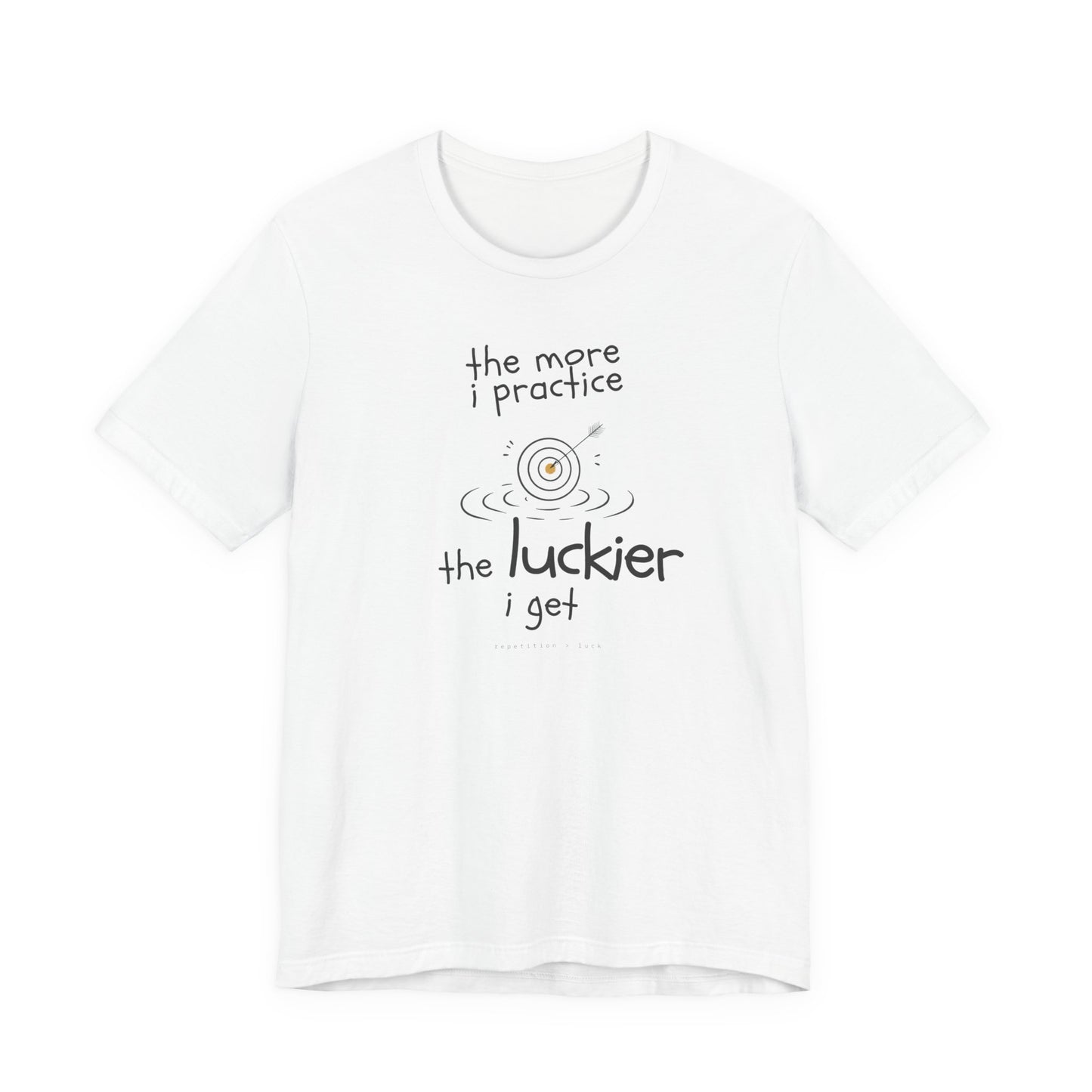 Minimalist motivational T-shirt design shown on a white shirt: hand-drawn cream lettering reads “the more i practice” above a sketched bullseye with an arrow and small mustard center, ripple lines underneath, then larger text reads “the luckier i get” with tiny mono text below that says “repetition > luck.”