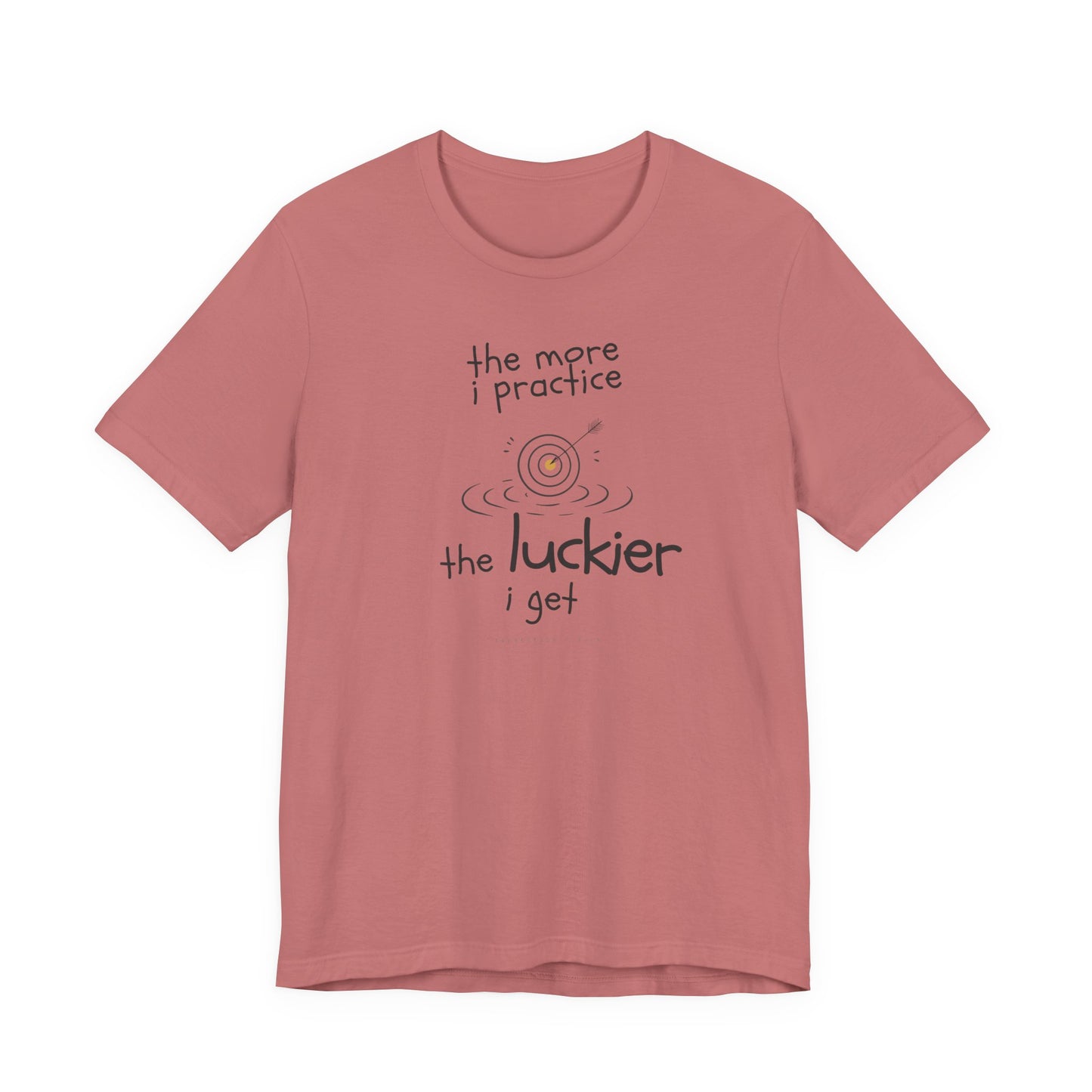 Minimalist motivational T-shirt design shown on a mauve coloured shirt: hand-drawn cream lettering reads “the more i practice” above a sketched bullseye with an arrow and small mustard center, ripple lines underneath, then larger text reads “the luckier i get” with tiny mono text below that says “repetition > luck.”