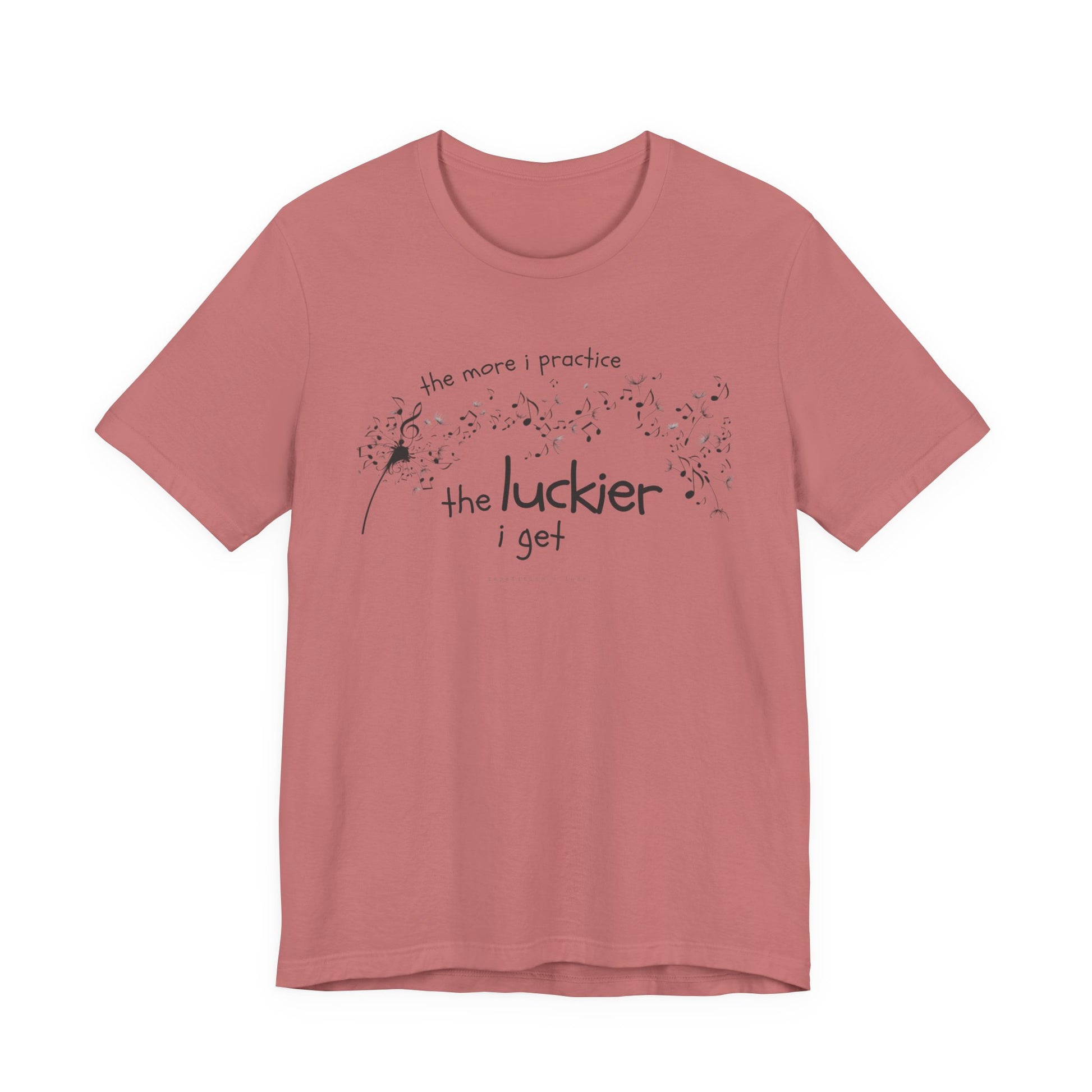Front view of a mauve Bella Canvas t-shirt with a clever music-themed graphic. The design shows a stylized guitar headstock and musical notes above text that reads: ‘The more I practice, the luckier I get.’ Soft 100% cotton shirt perfect for musicians and music teachers.