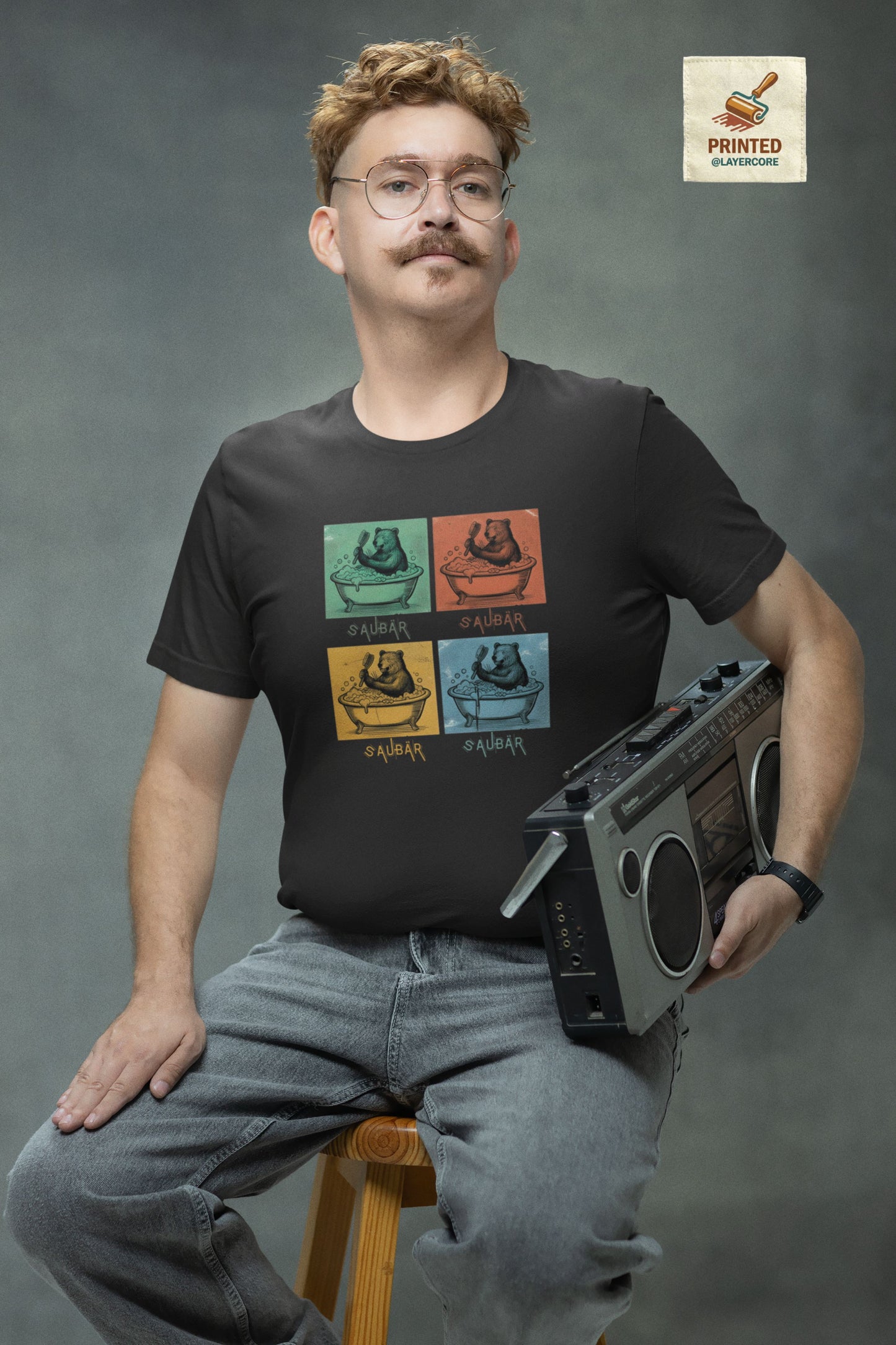 Vintage-Illustration eines Bären in einer Badewanne mit dem Schriftzug Saubär auf einem dunkel grauem T-Shirt welches von einem jungen Mann im vintage look getragen wird