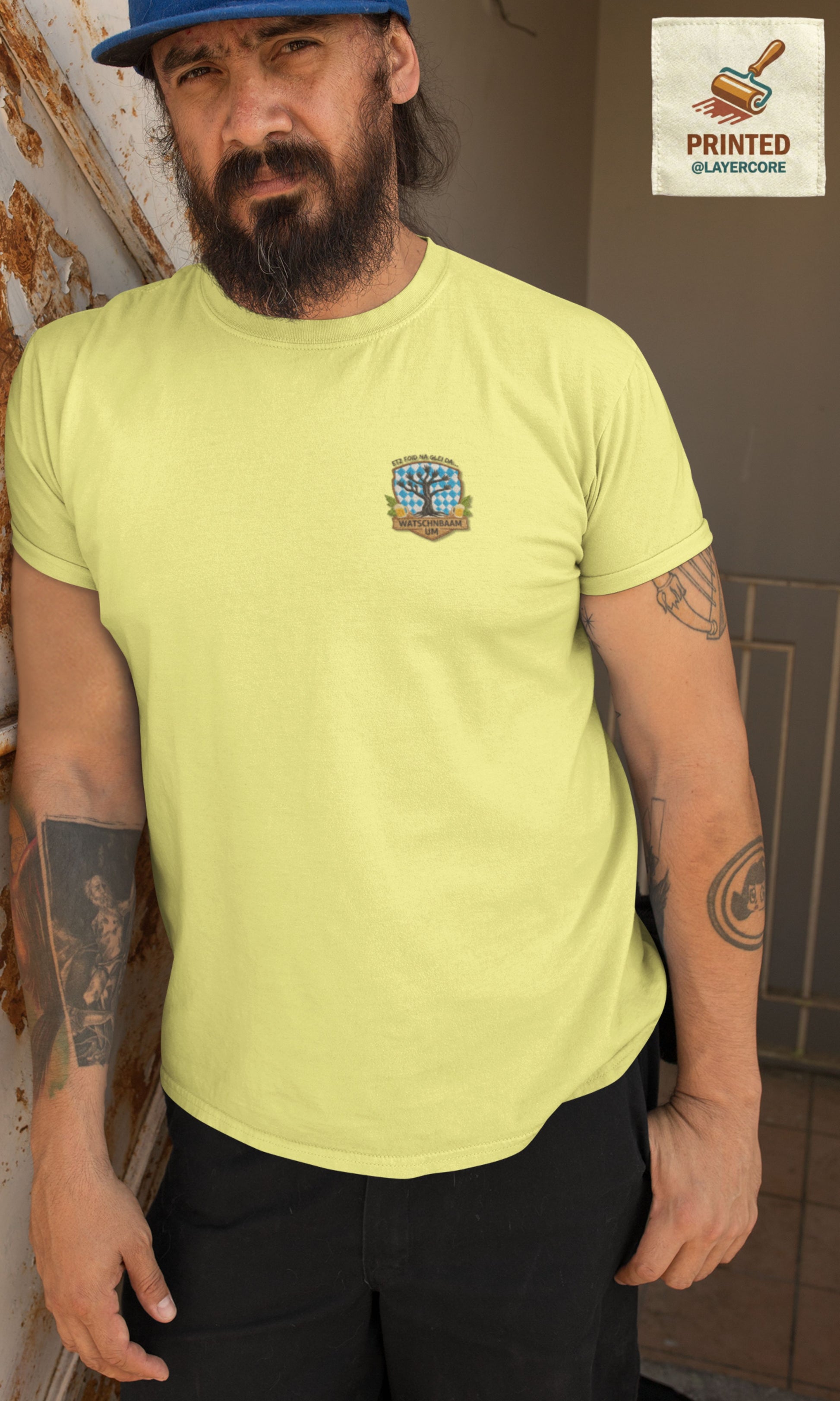 Watschnbaam gelbes T-Shirt in Stick-Optik (Druck), bayerisches Wappen mit Händen als Äste, Bierkrügen und Hopfen. Mann mittleren Alters mit Bart und Tattoos trägt das Shirt