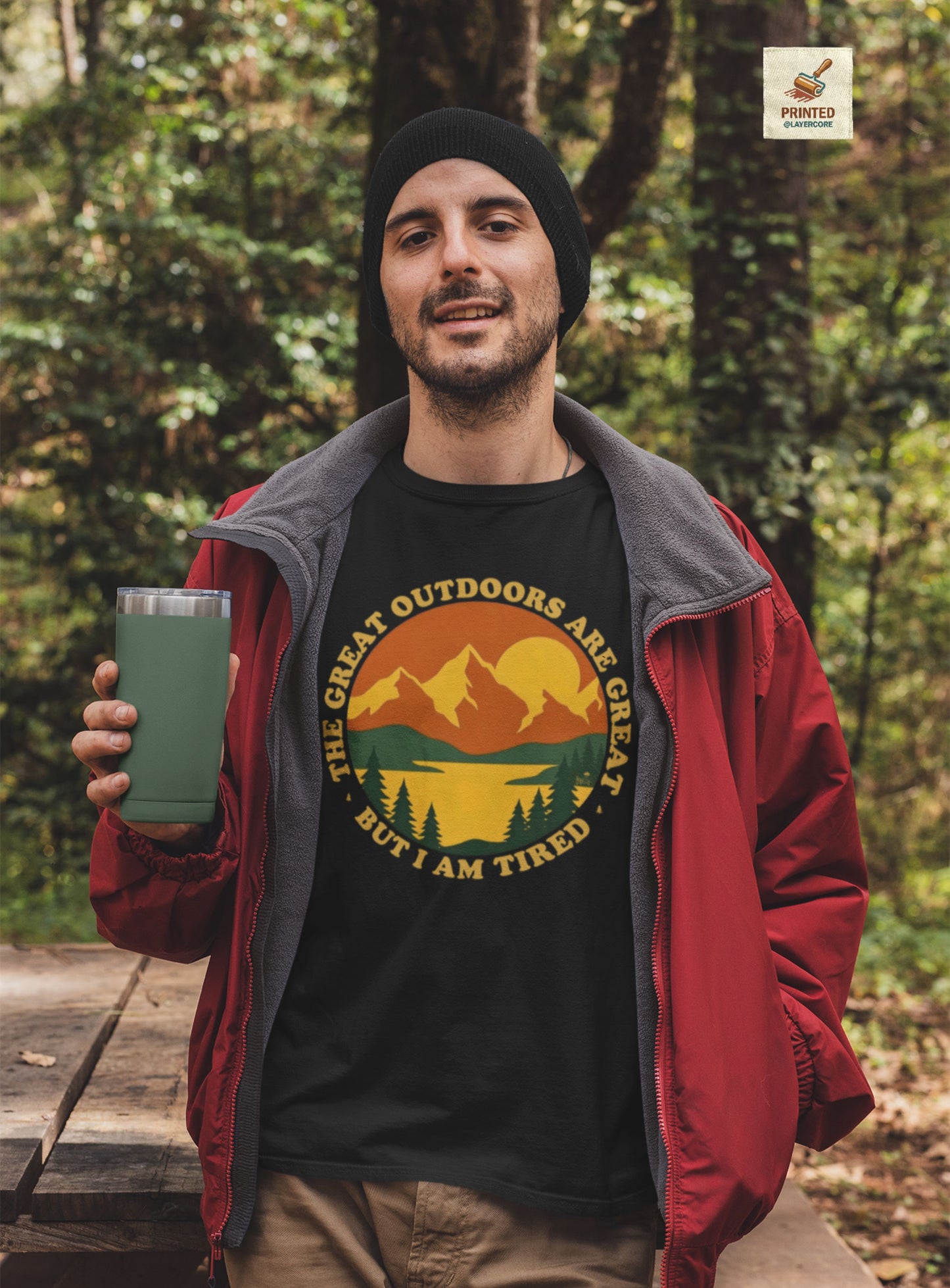 Retro 70s Berglandschaft schwarzes T-Shirt, getargen von einem jungen Mann draußen in der Natur, mit "The Great Outdoors are great but I am tired" Schriftzug.