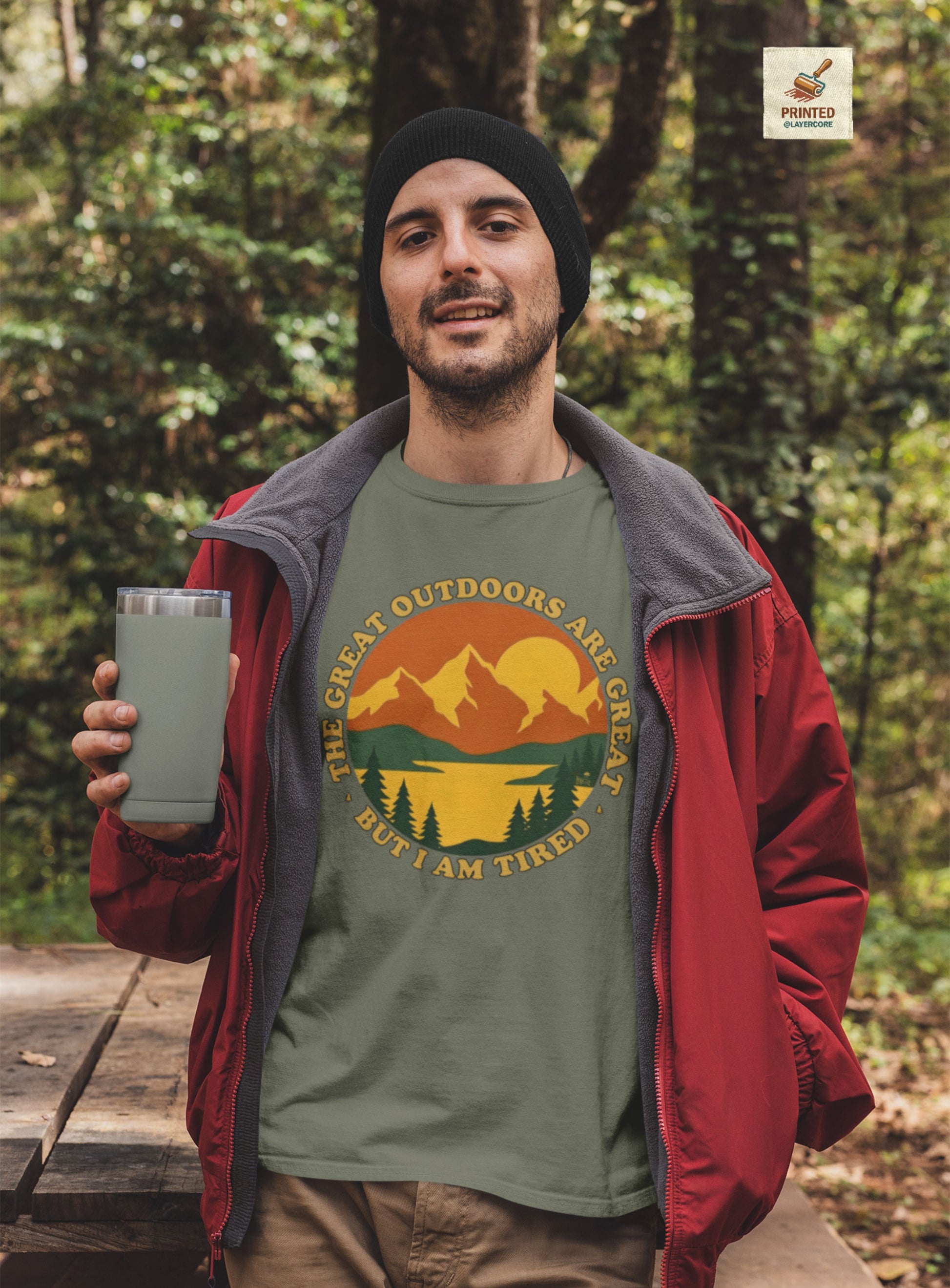 Retro 70s Berglandschaft military grünes T-Shirt, getargen von einem jungen Mann draußen in der Natur, mit "The Great Outdoors are great but I am tired" Schriftzug.