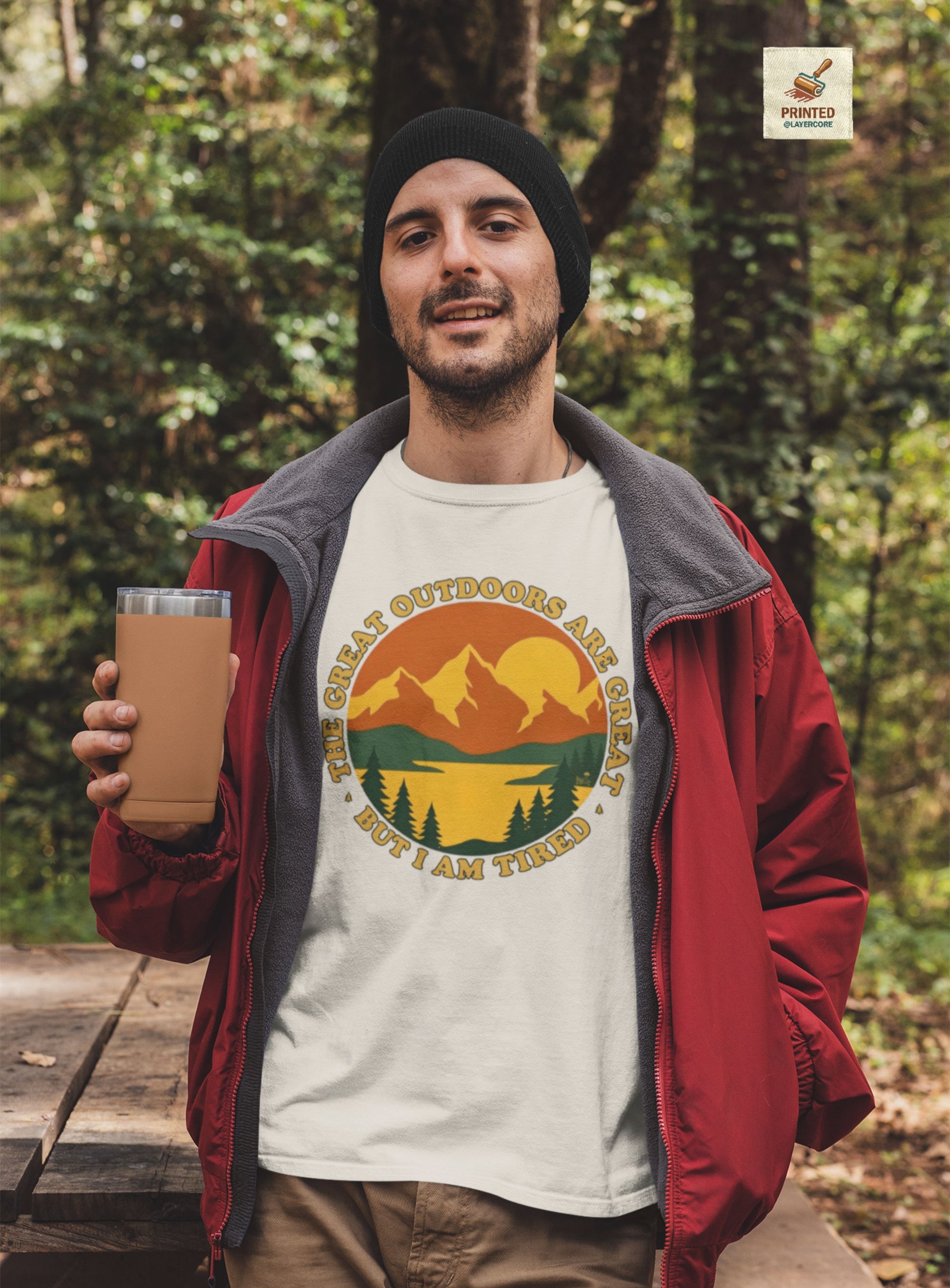 Retro 70s Berglandschaft natural farbenes T-Shirt, getargen von einem jungen Mann draußen in der Natur, mit "The Great Outdoors are great but I am tired" Schriftzug.