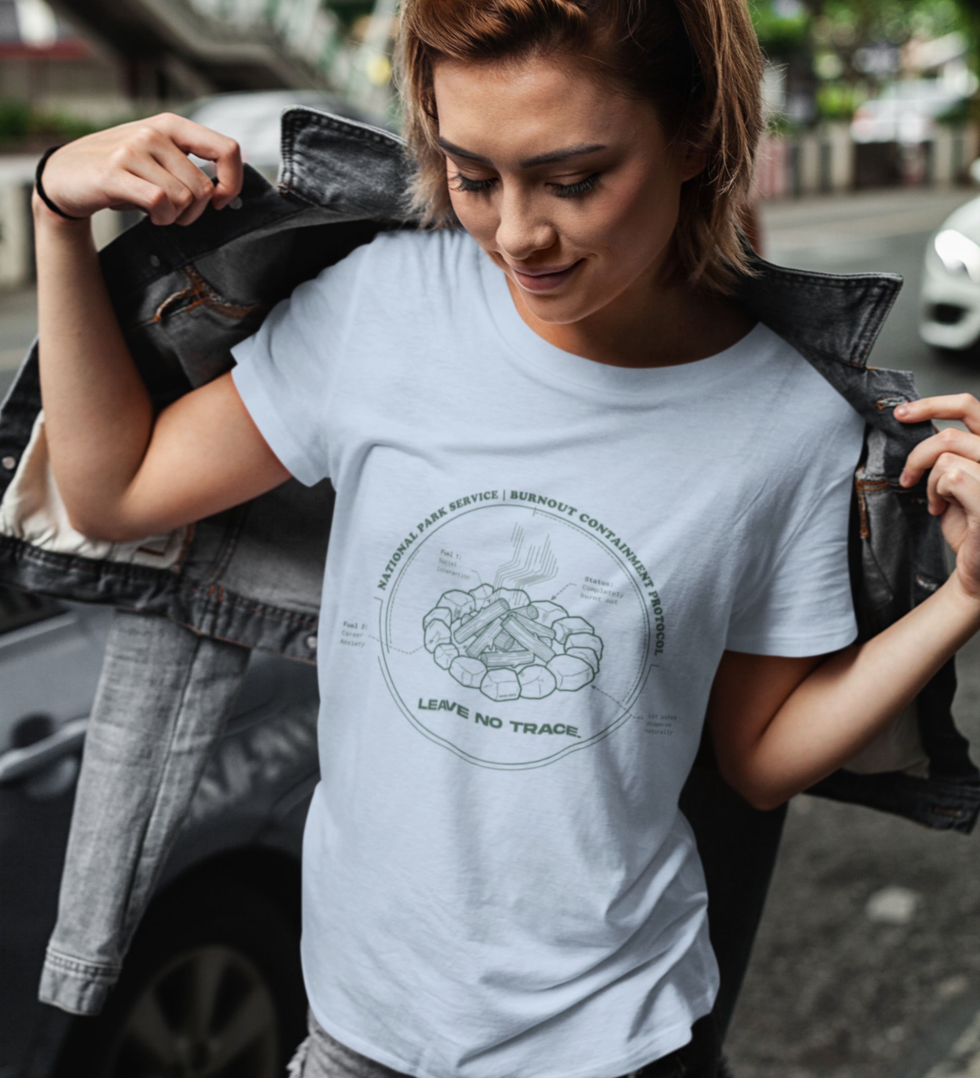 Technisches Diagramm eines Lagerfeuers mit Text Burnout Containment Protocol auf hellblauem T-Shirt, getragen von einer jungen Faru mit Lederjacke. Anti-Gorpcore Streetwear.