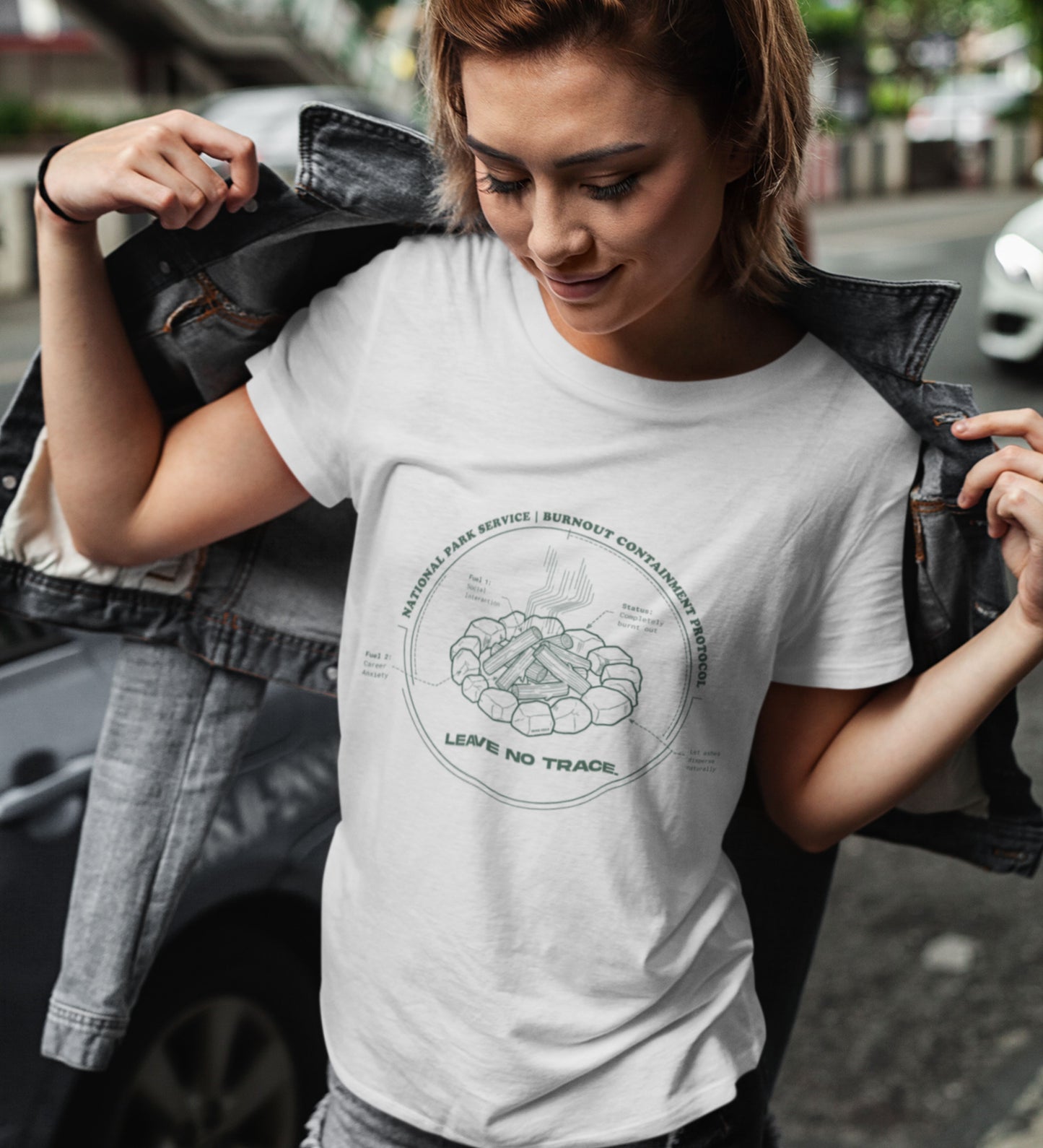 Technisches Diagramm eines Lagerfeuers mit Text Burnout Containment Protocol auf grauem T-Shirt, getragen von einer jungen Faru mit Lederjacke. Anti-Gorpcore Streetwear.