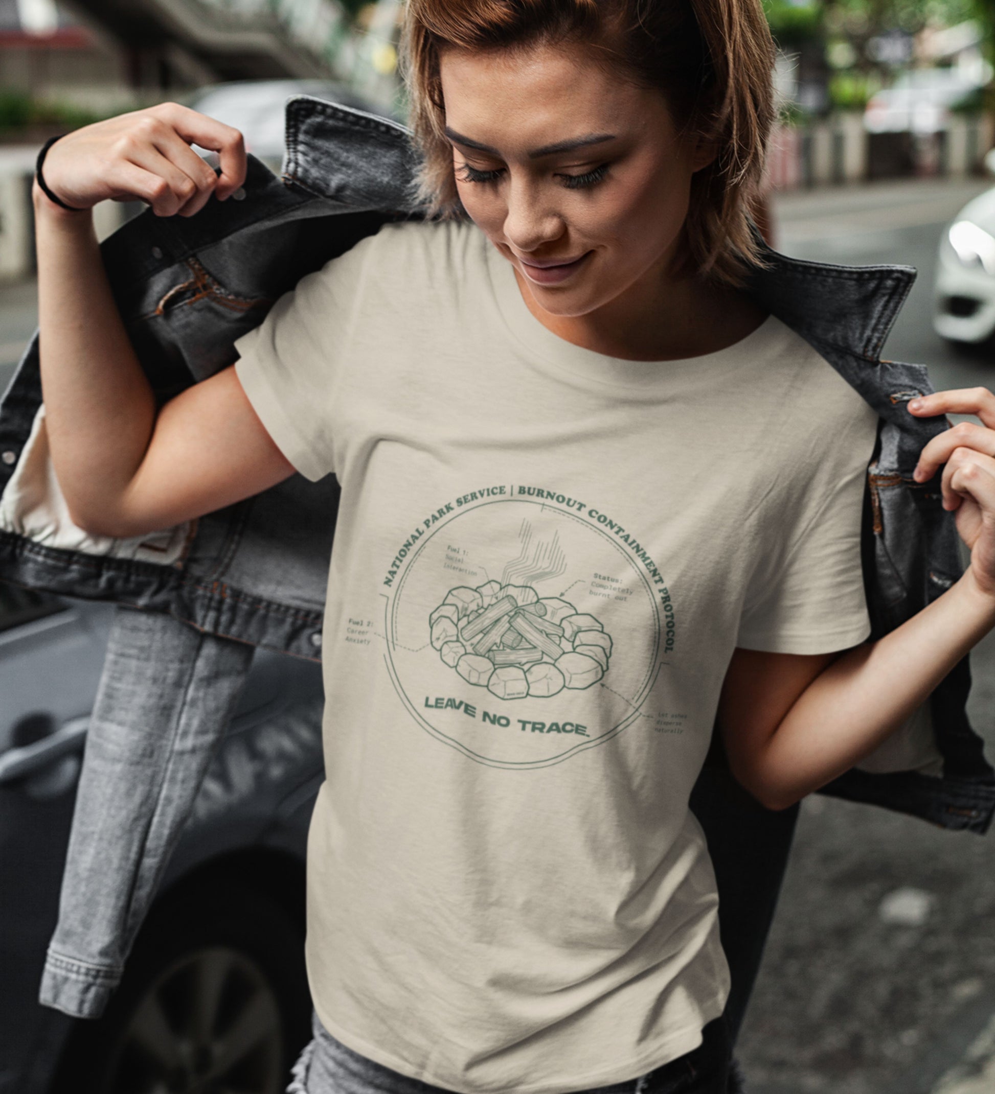 Technisches Diagramm eines Lagerfeuers mit Text Burnout Containment Protocol auf beigem T-Shirt, getragen von einer jungen Faru mit Lederjacke. Anti-Gorpcore Streetwear.