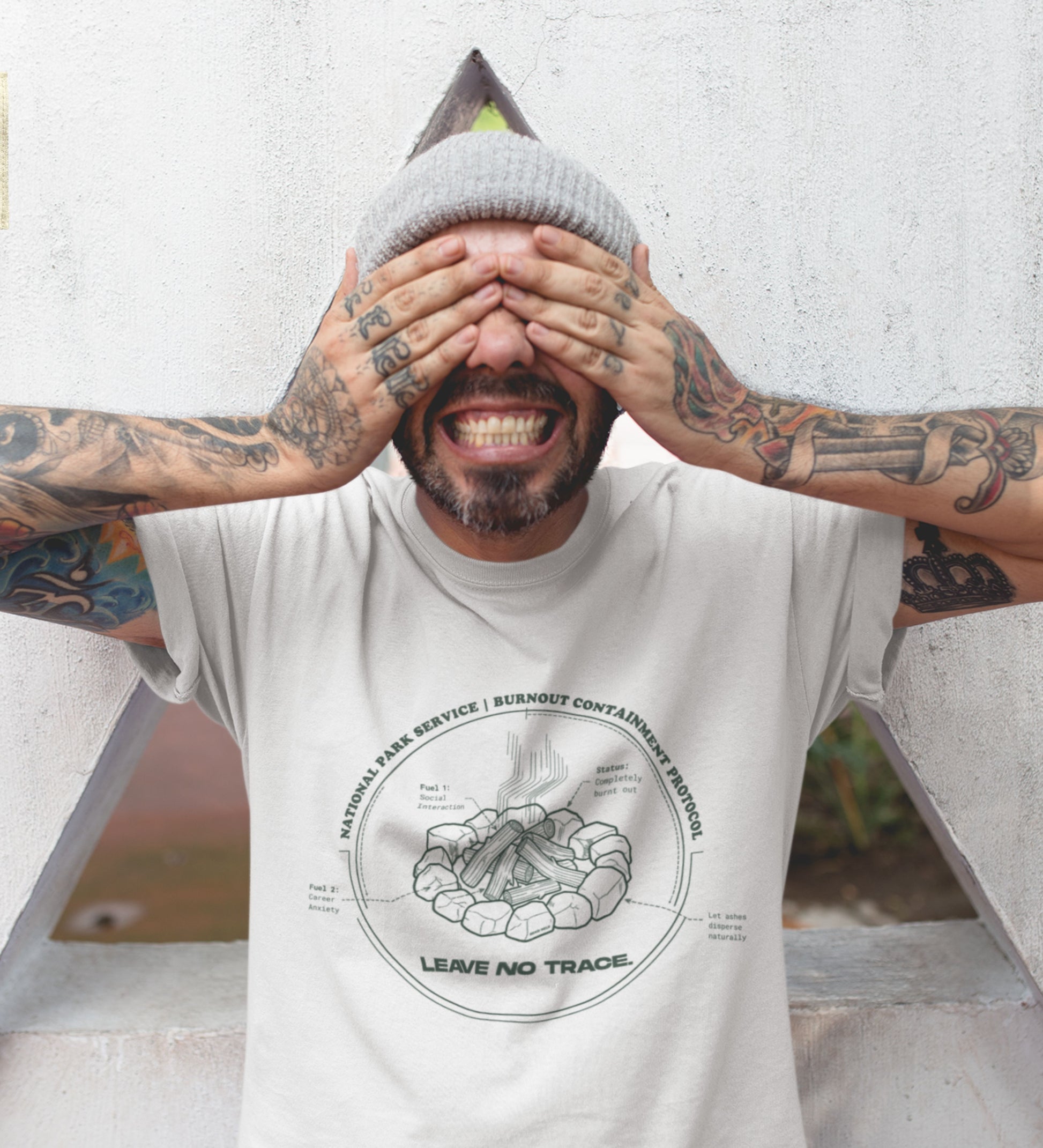 Technisches Diagramm eines Lagerfeuers mit Text Burnout Containment Protocol auf grauem T-Shirt, getragen von einem jungen Mann mit Tattoos. Anti-Gorpcore Streetwear.