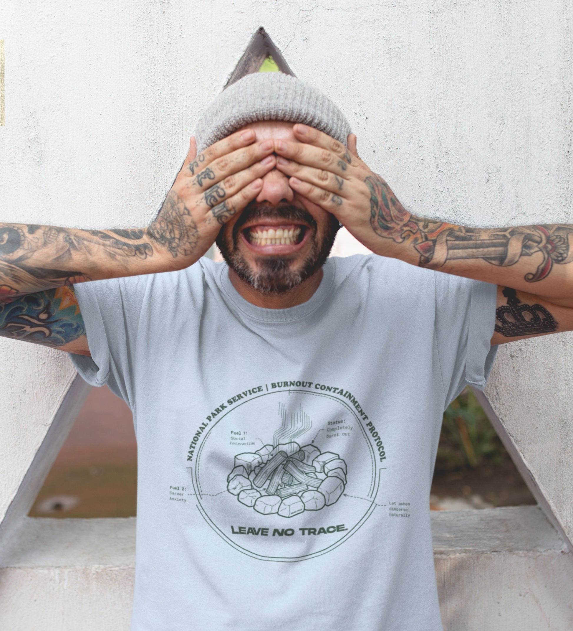 Technisches Diagramm eines Lagerfeuers mit Text Burnout Containment Protocol auf hellblauem T-Shirt, getragen von einem jungen Mann mit Tattoos. Anti-Gorpcore Streetwear.