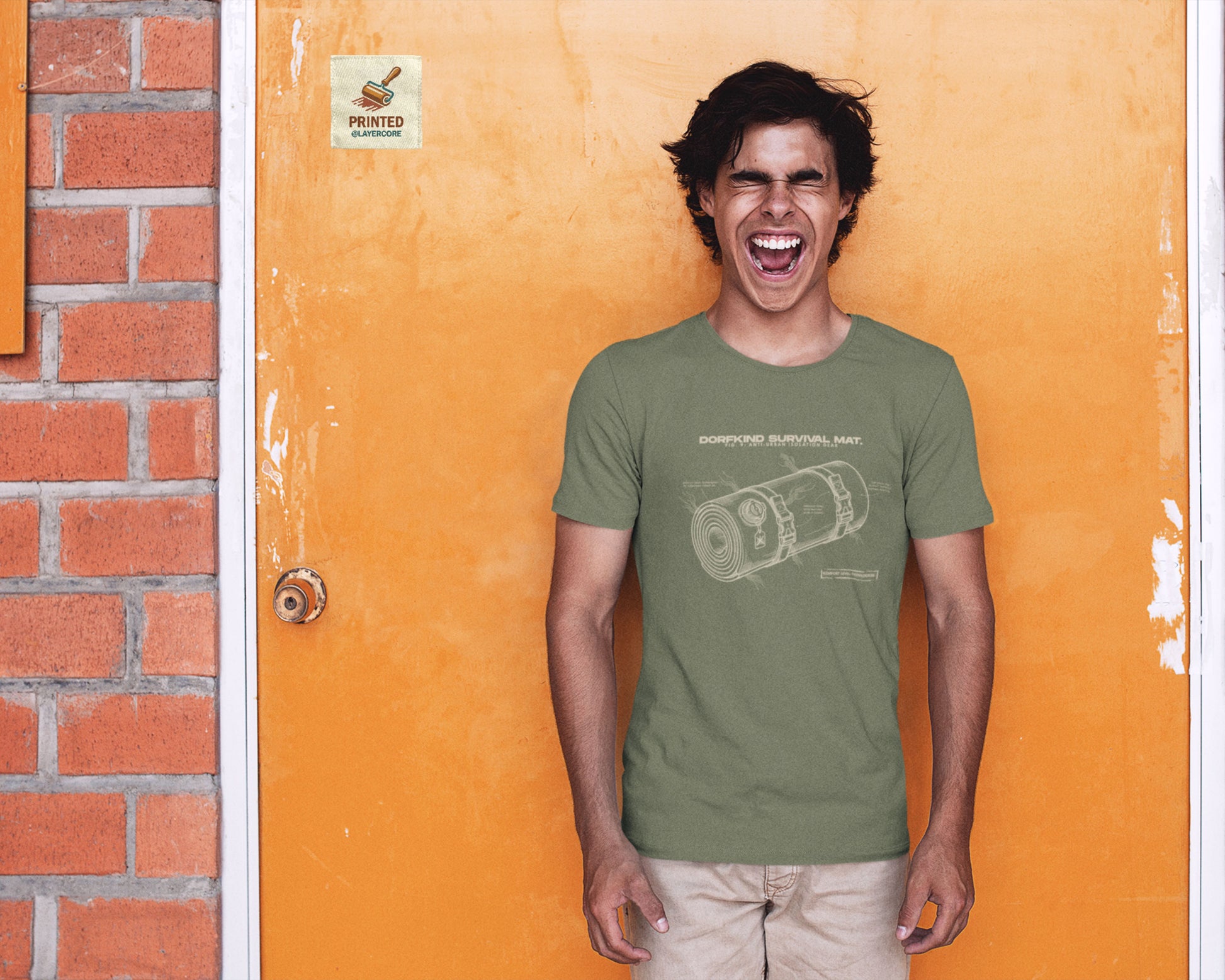Technische Blueprint-Zeichnung einer Isomatte mit ironischen Texten zum Dorfleben auf einem military grünem T-Shirt, getragen von einem jungen Mann. Anti-Gorpcore Design.