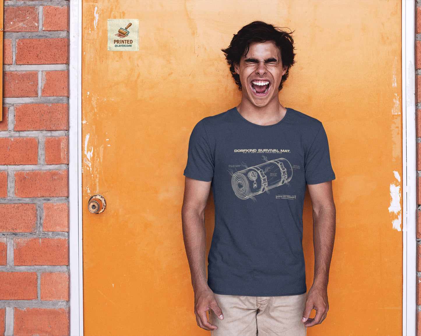 Technische Blueprint-Zeichnung einer Isomatte mit ironischen Texten zum Dorfleben auf einem navy blauem farbenem T-Shirt, getragen von einem jungen Mann. Anti-Gorpcore Design.