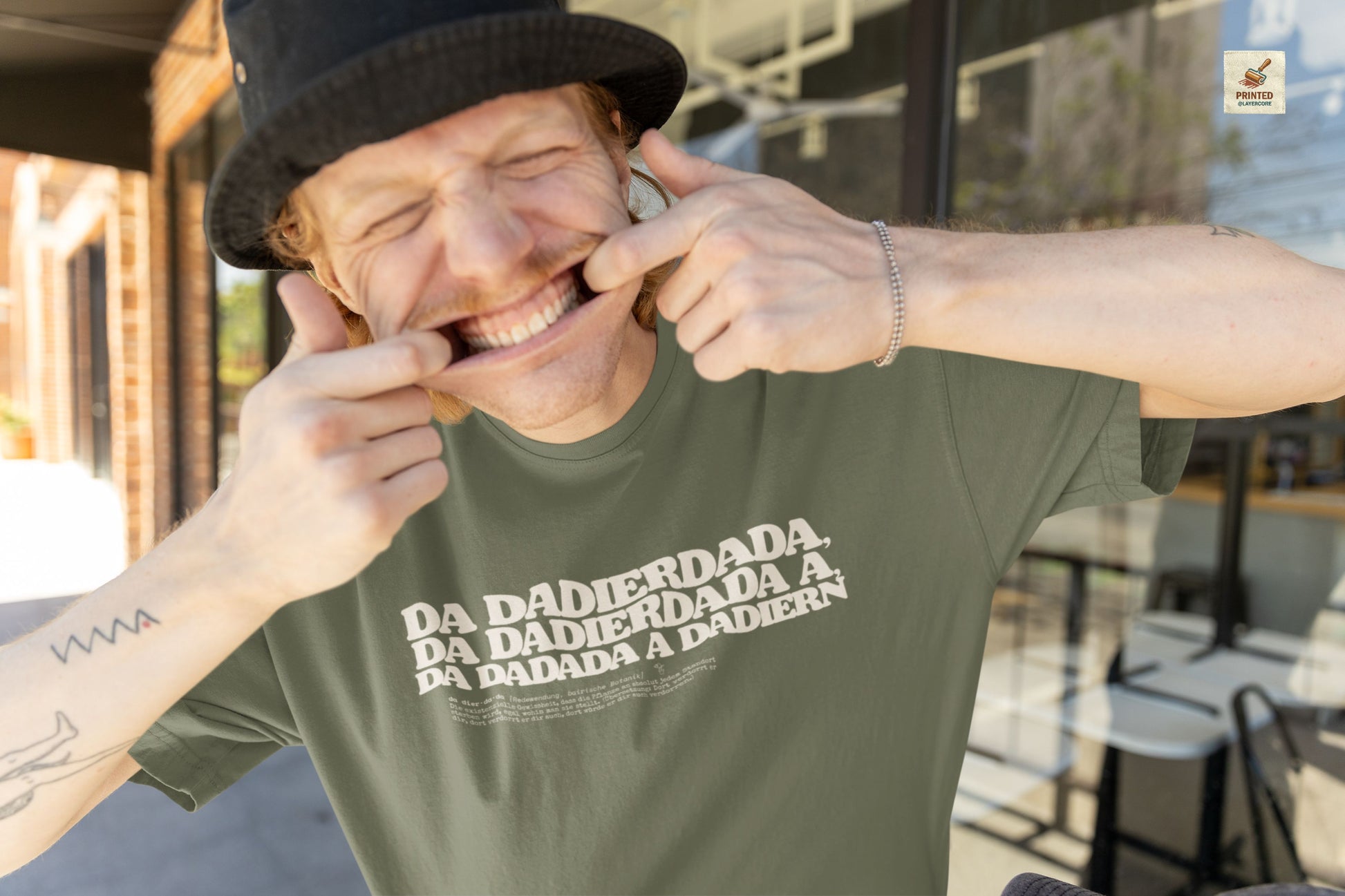 Da dadierdada grünes T-Shirt. Bayerischer Zungenbrecher und Wortwitz im todernsten Lexikon-Design. Schweres Gildan 5000 Baumwollshirt, getragen von einem jungen Mann.