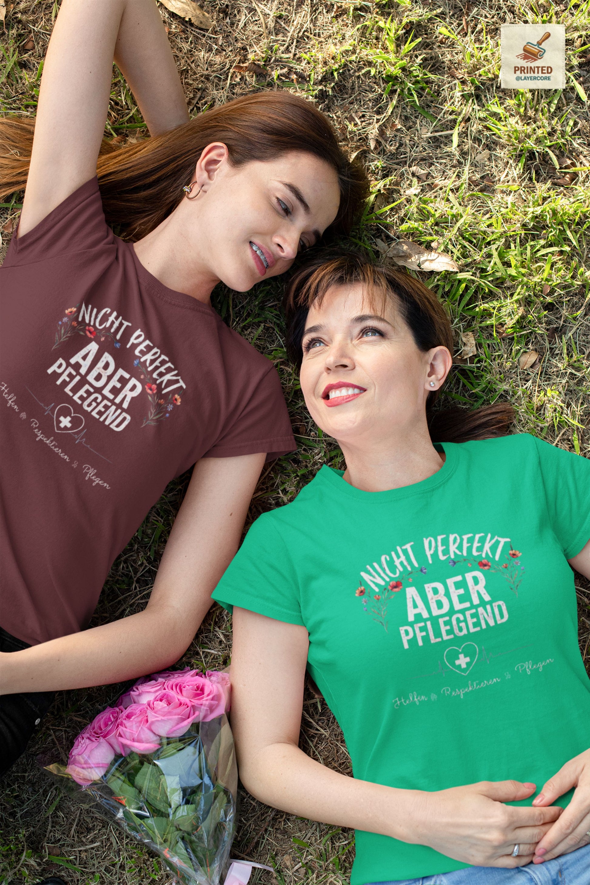 T-Shirt Nicht perfekt aber pflegend mit Blumenkranz und EKG Herz für Krankenschwestern und Pflegekräfte im Schichtdienst, getragen von zwei Frauen, welche auf einer Wiese liegen