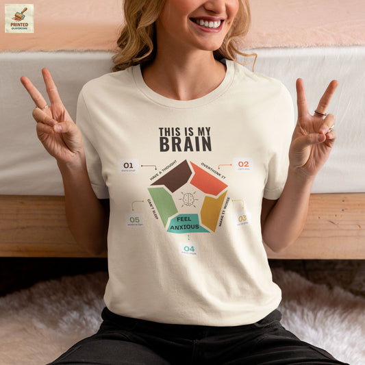 Minimalist natural coloured t-shirt showing a structured overthinking cycle with segmented diagram and clean typography, representing anxiety, sleeplessness, and mental loops in a subtle and modern visual style, worn by a young woman