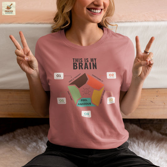 Minimalist mauve coloured t-shirt showing a structured overthinking cycle with segmented diagram and clean typography, representing anxiety, sleeplessness, and mental loops in a subtle and modern visual style, worn by a young woman
