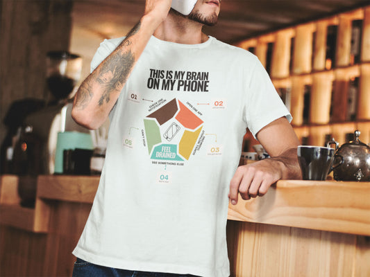 Minimalist doomscrolling cycle t-shirt design reading “This Is My Brain on My Phone” with screen time steps and “Feel Drained” center, worn by a young man