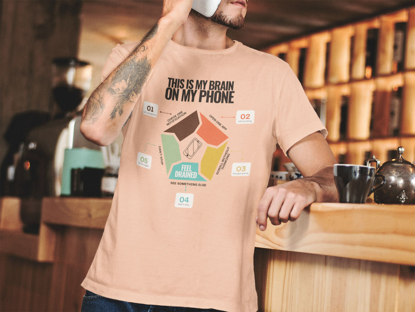 Minimalist doomscrolling cycle t-shirt  in peach, design reading “This Is My Brain on My Phone” with screen time steps and “Feel Drained” center worn by a young man