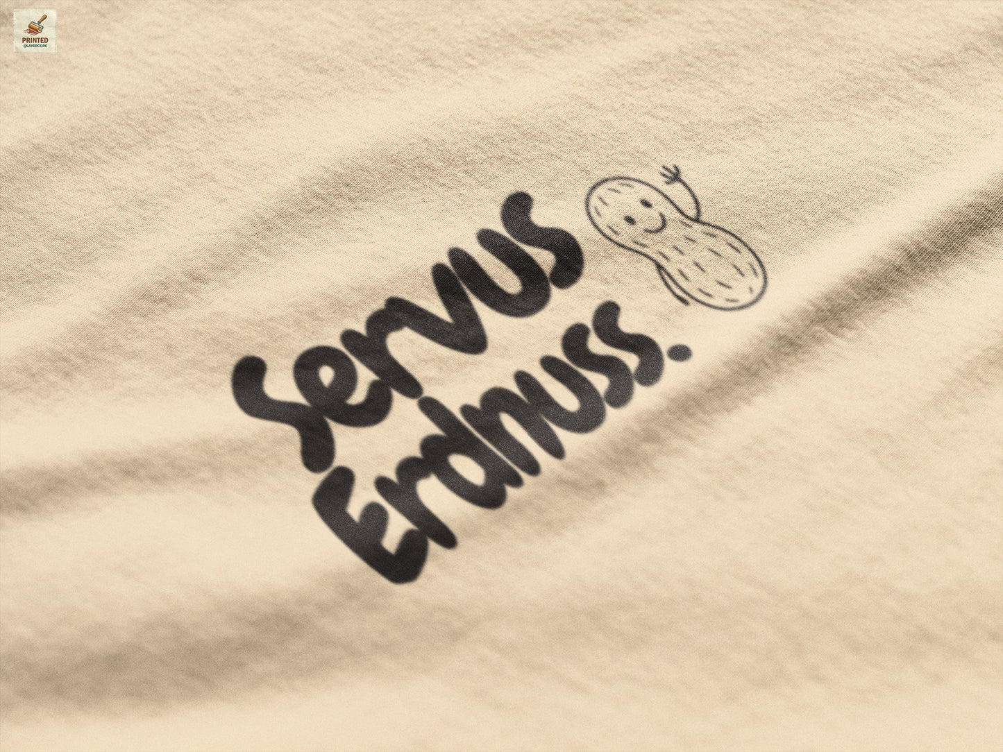 Servus Erdnuss Brustmotiv mit Dialekt-Text und kleiner Erdnussfigur auf naturfarbenem Shirt