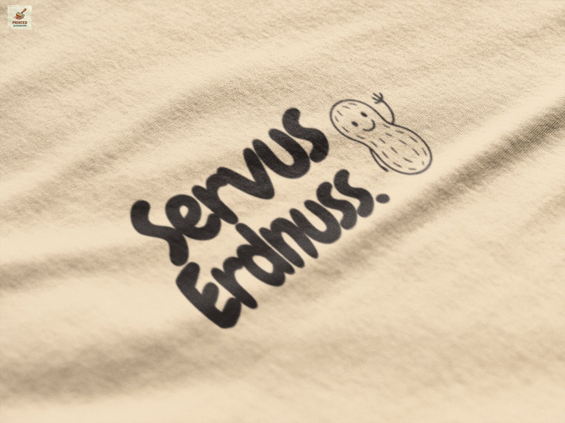 Servus Erdnuss Brustmotiv mit Dialekt-Text und kleiner Erdnussfigur auf naturfarbenem Shirt