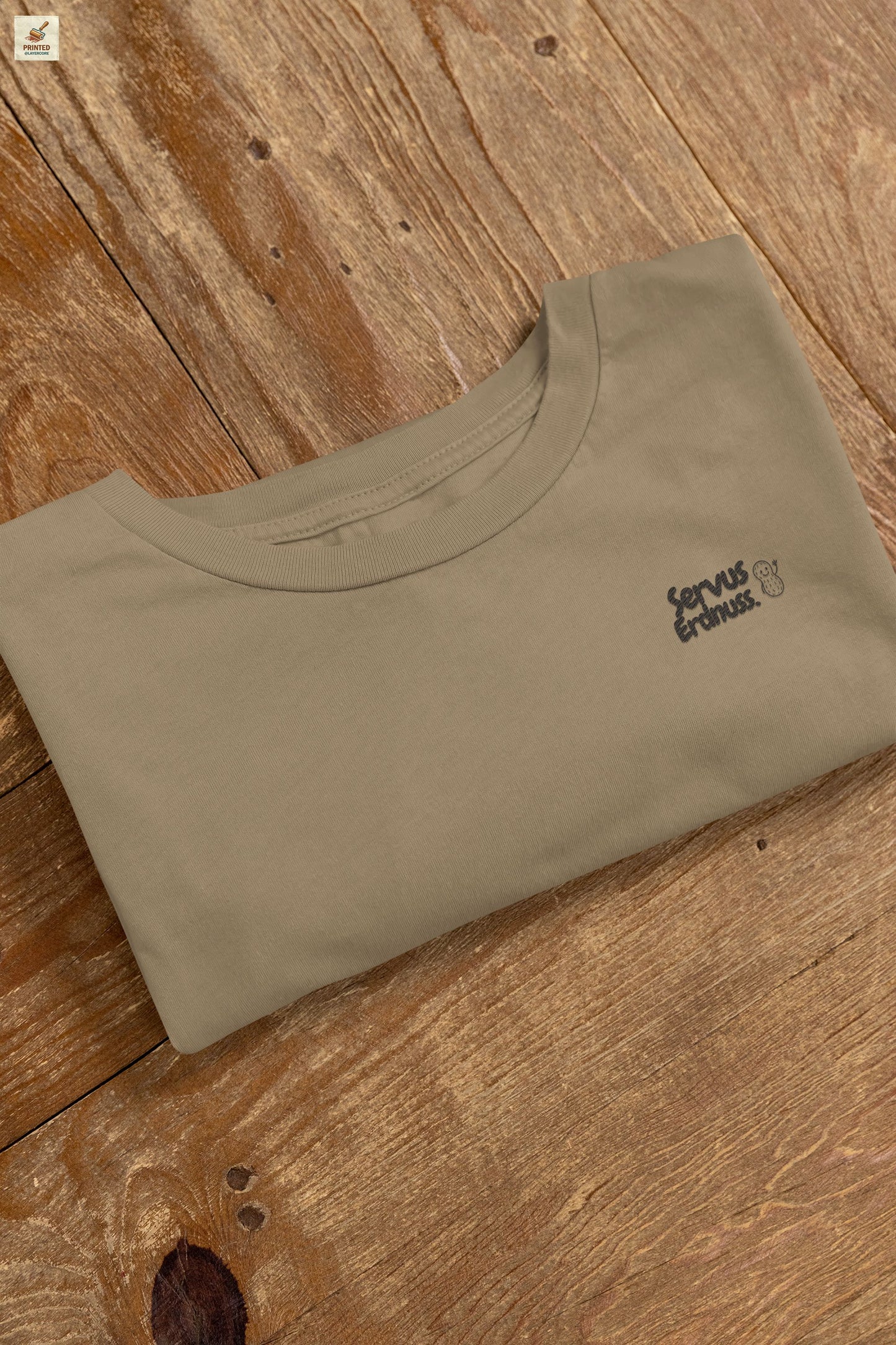 Servus Erdnuss Brustmotiv mit Dialekt-Text und kleiner Erdnussfigur auf military grünem Shirt