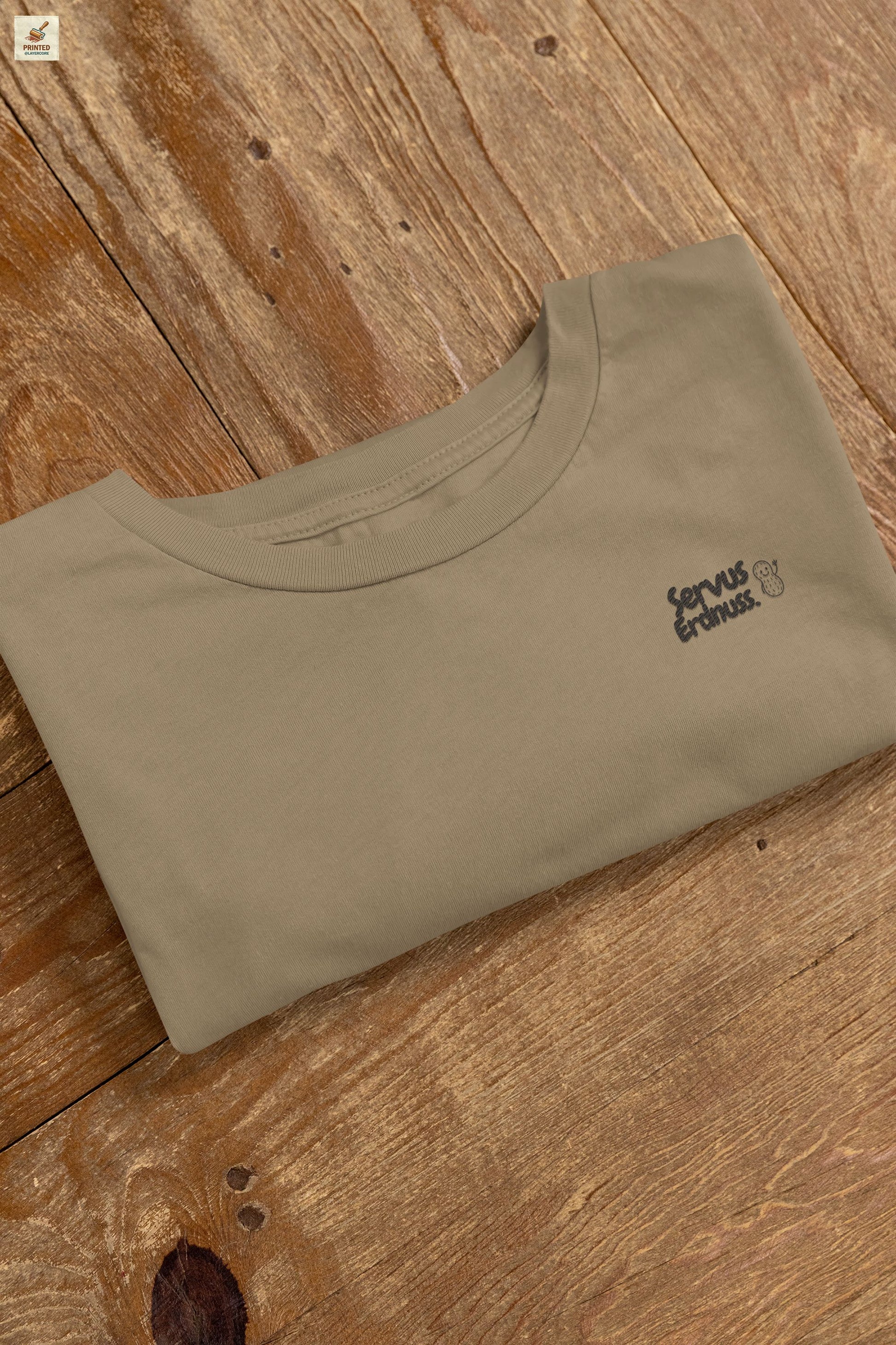 Servus Erdnuss Brustmotiv mit Dialekt-Text und kleiner Erdnussfigur auf military grünem Shirt