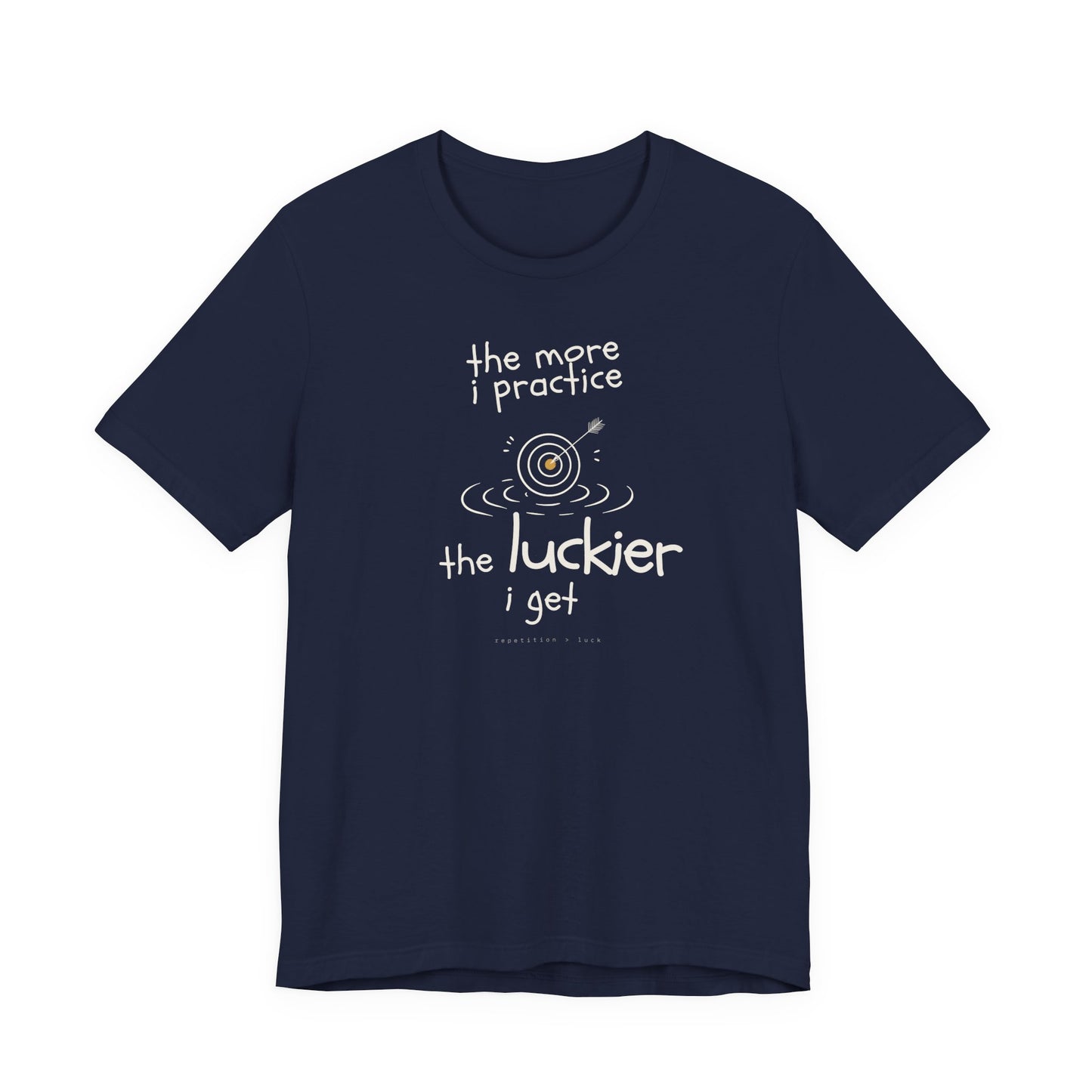 Minimalist motivational T-shirt design shown on a dark blue shirt: hand-drawn cream lettering reads “the more i practice” above a sketched bullseye with an arrow and small mustard center, ripple lines underneath, then larger text reads “the luckier i get” with tiny mono text below that says “repetition > luck.”
